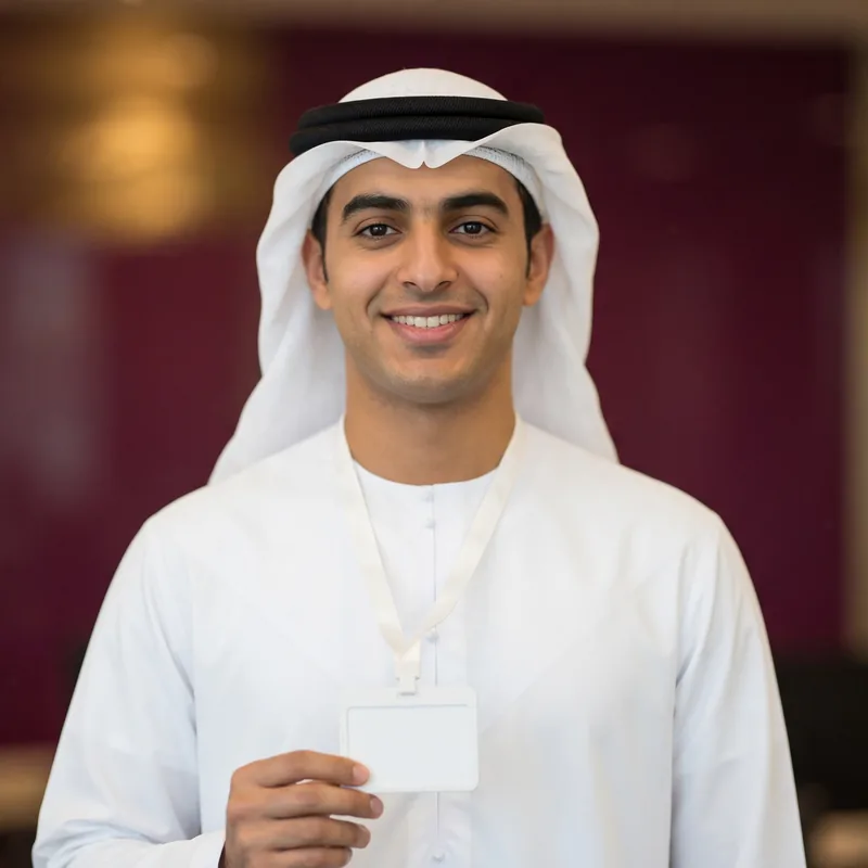 Smiling new Emirati employee holding his staff badge on his first day